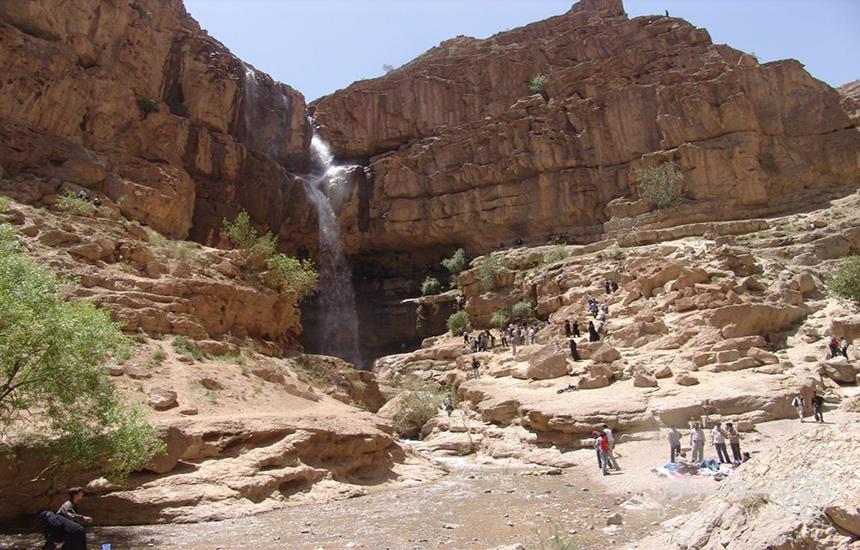 آبشار دره‌گاهان تفت در دل کوه و جمعیتی از مردم پای آبشار